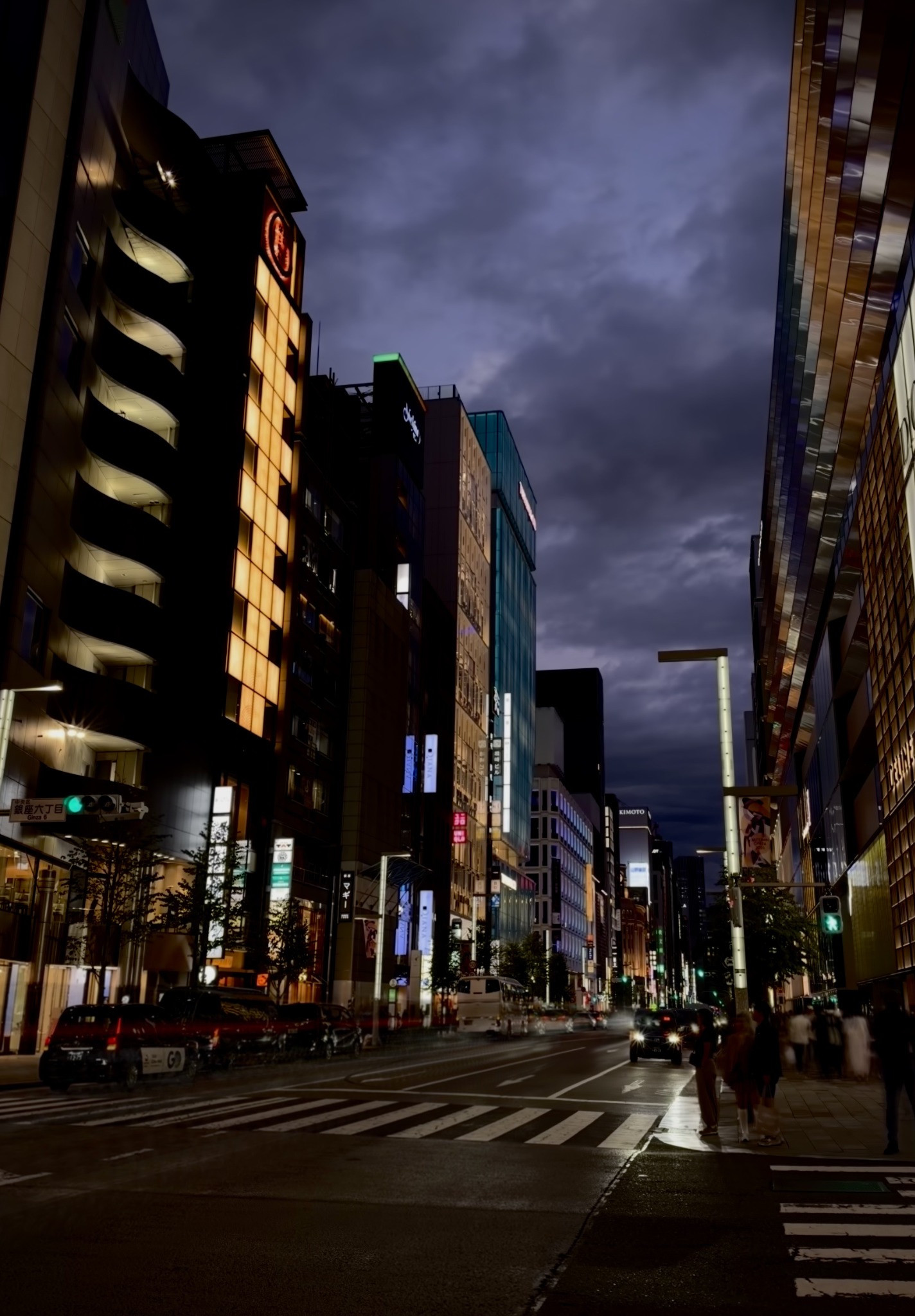 A violet-grey night sky above illuminated buildings and a pedestrian crossing in Ginza.